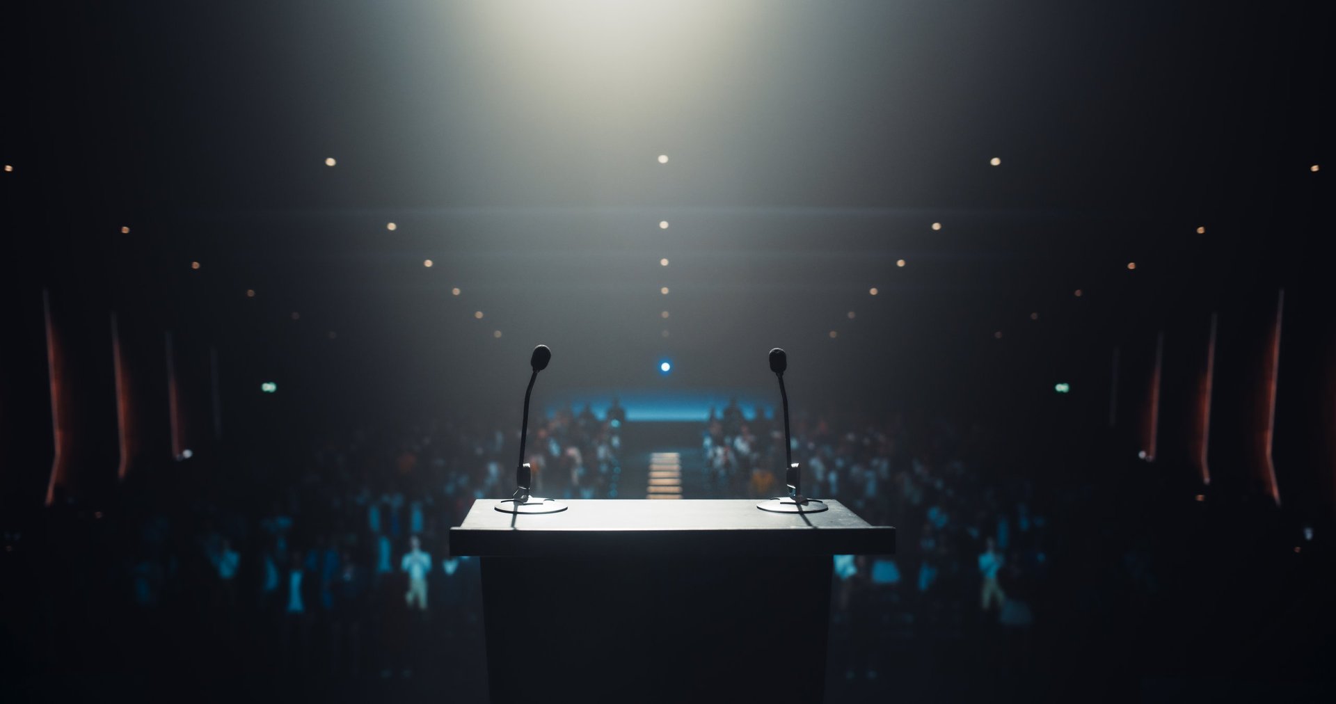 Modern Conference Stage With Two Microphones Under Spotlight in a Dark Lit Auditorium.