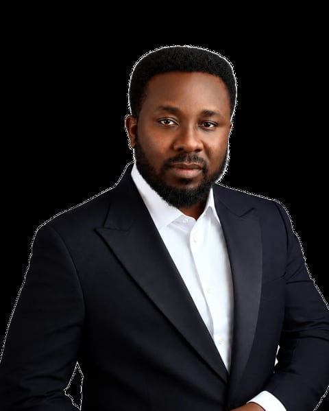 Professional headshot of a Black man with a beard wearing a dark navy blazer and white dress shirt against a black background
