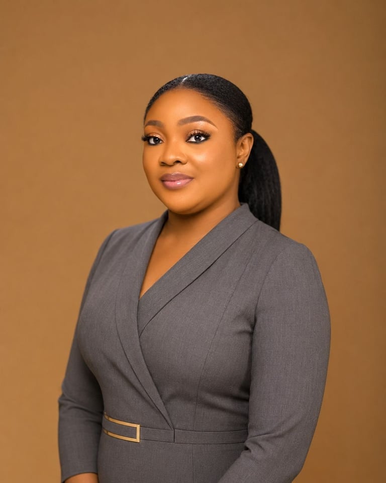 Professional portrait of a woman wearing a gray blazer against a tan background